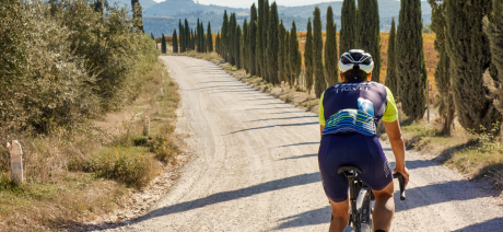 The back of a gravel cyclist riding on the white gravel roads of Tuscany