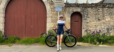 Cyclist in front of an old wall and French village road signs
