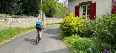 Cyclist riding on a narrow road alongside a house