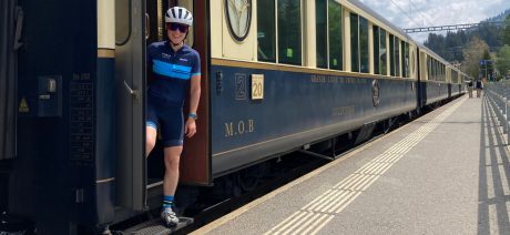 Cyclist standing at the entrance of a classic Swiss train