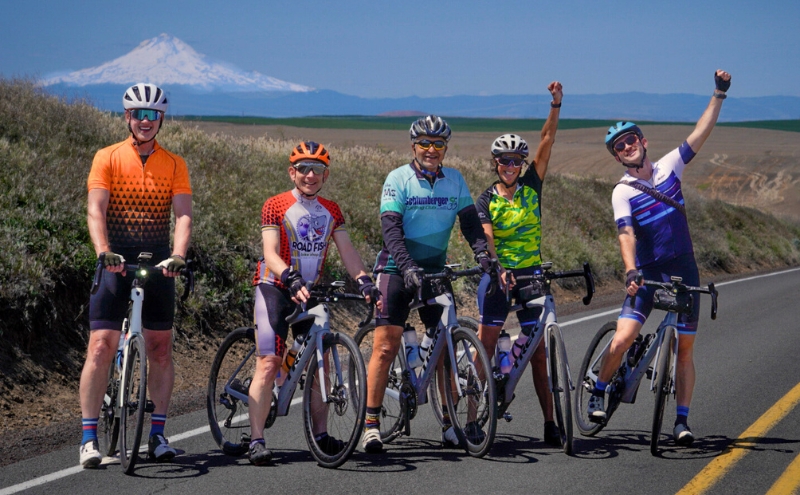Group of cyclists posing in the foreground with Mt.Hood in the background